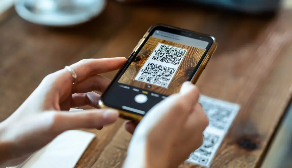 Young woman hands using the smart phone to scan the qr code to select food menu in the restaurant. QR Code Example