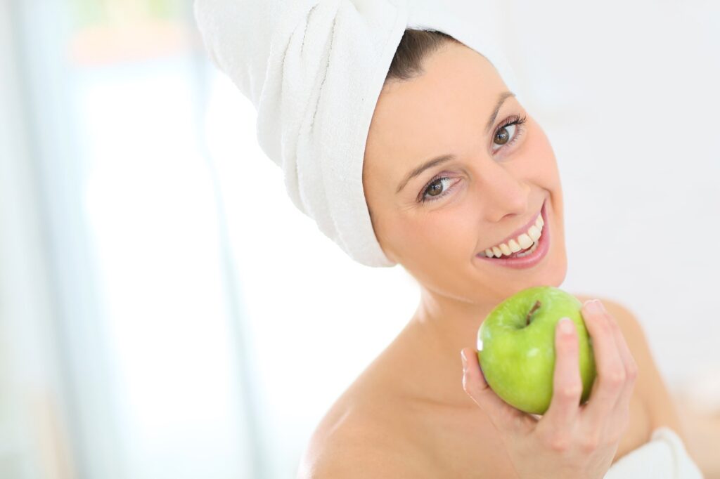 Woman wrapped in towel holding an apple