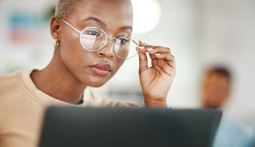 Office, computer and black woman with glasses, serious or reading email, online research or report. Laptop, concentration and African journalist proofreading article for digital news website or blog Business Owner Blogging on a Company Blog