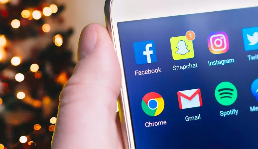 holiday-social Social media apps on phone in front of Christmas tree