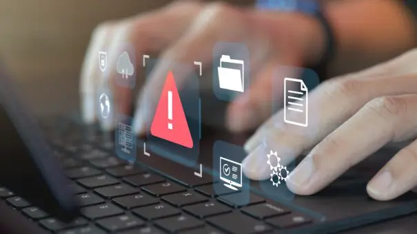 Developer programmer using laptop with warning triangle sign for alert found error and maintenance concept Fingers on keyboard, with icons showing errors and issues