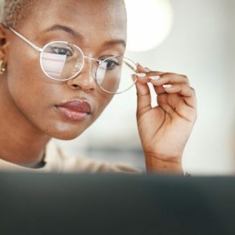 Office, computer and black woman with glasses, serious or reading email, online research or report. Laptop, concentration and African journalist proofreading article for digital news website or blog Business Owner Blogging on a Company Blog