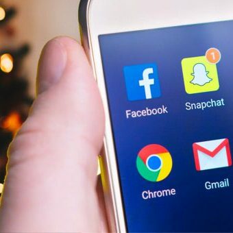 holiday-social Social media apps on phone in front of Christmas tree