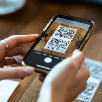 Young woman hands using the smart phone to scan the qr code to select food menu in the restaurant. QR Code Example