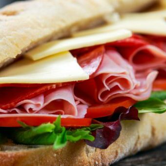 Sandwich with lettuce, slices of fresh tomatoes, salami, hum and cheese. a picture of a sub to demonstrate user experience